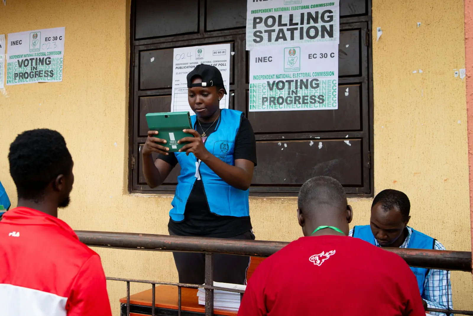 An election official checking voter details on a tablet at a polling unit
