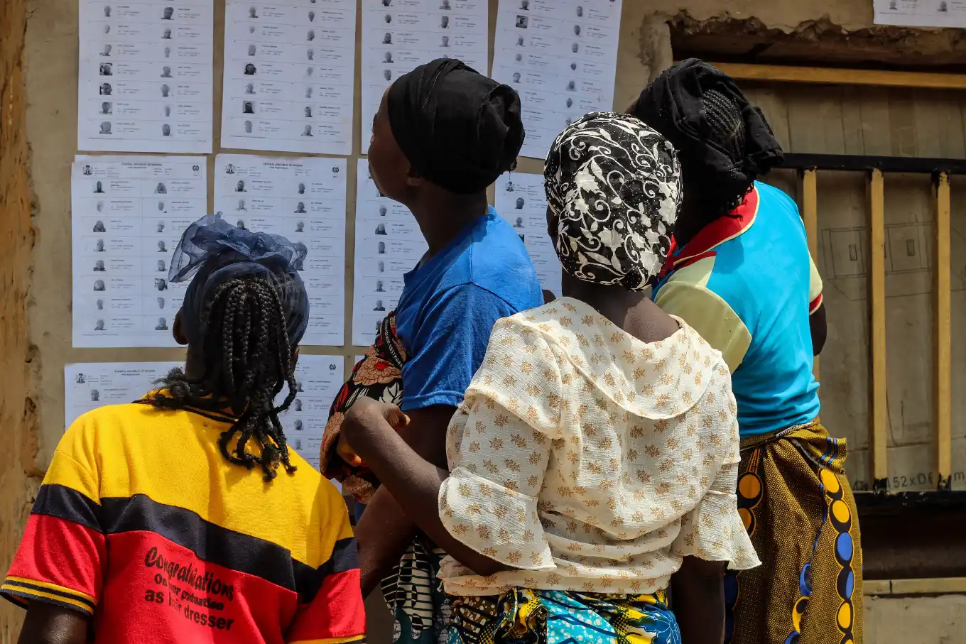 Voters reading the voter register pasted on a wall